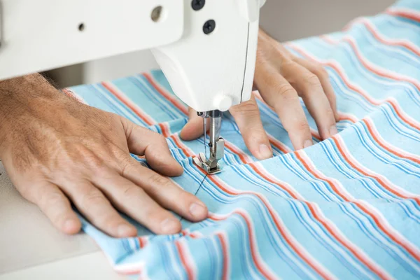 Tailor Sewing Fabric At Workbench
