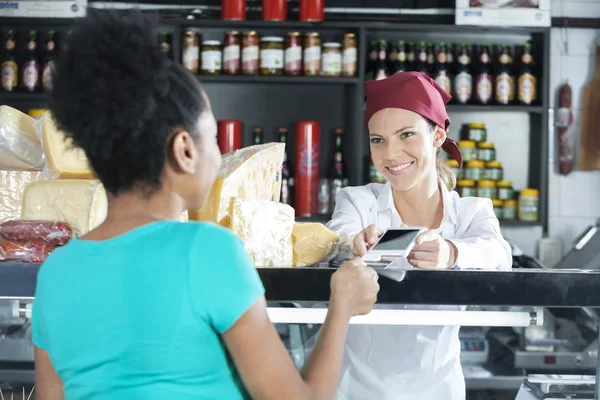 Saleswoman Accepting Payment From Customer In Cheese Shop