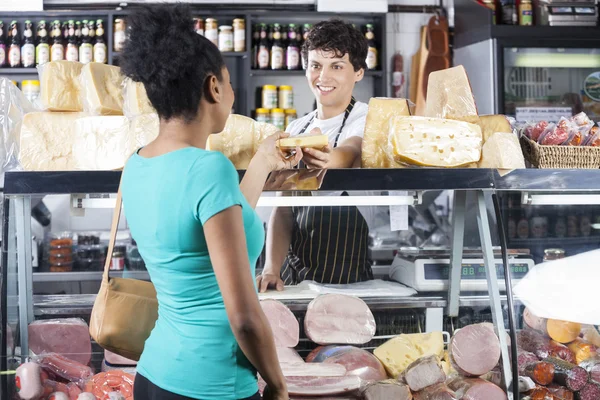 Smiling Salesman Selling Cheese To Female Customer