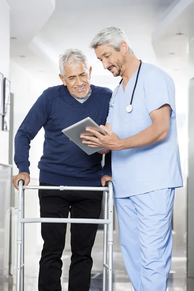 Physiotherapist Showing Reports On Digital Tablet To Senior Man