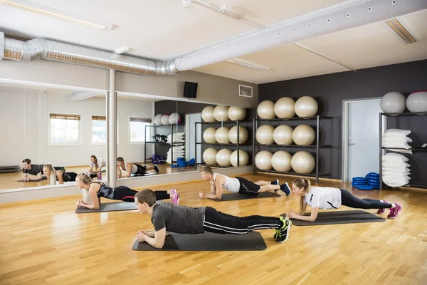 Friends Performing Plank Exercise In Gym