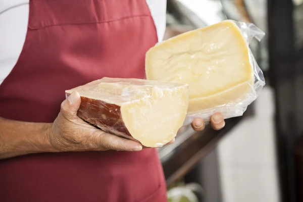 Salesman Holding Packed Cheese Pieces In Shop