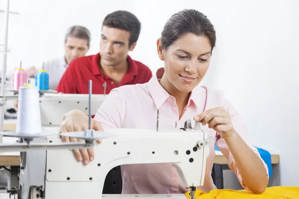Smiling Tailor Adjusting Sewing Machine At Factory