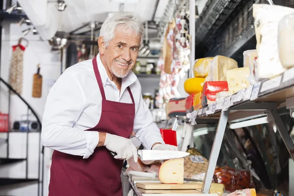 Happy Salesman Slicing Cheese In Shop