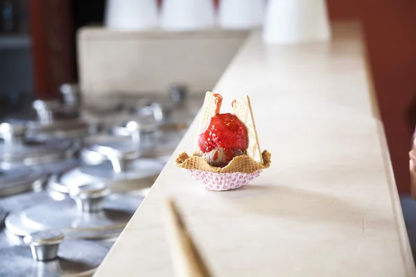 Ice Cream With Strawberry Syrup In Waffle Bowl On Counter