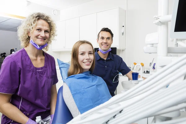 Smiling Patient With Male And Female Dentists In Clinic