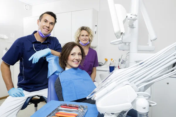 Smiling Patient With Dentist And Assistant At Clinic