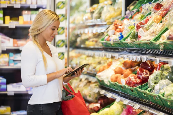 Woman Using Tablet Computer In Grocery Store