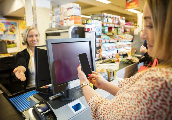 Cashier Gesturing While Female Customer Doing NFC Payment