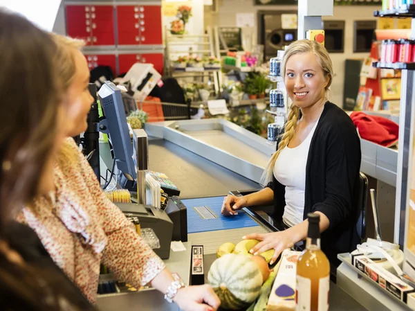 Cashier Smiling While Customers Standing At Checkout Counter