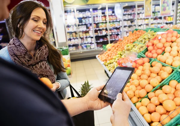 Customer Using Digital Tablet With Woman In Grocery Store