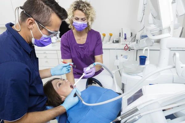 Dentist With Assistant Examining Patient In Clinic