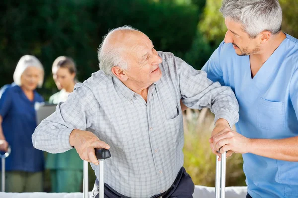 Male And Female Nurses Helping Senior People