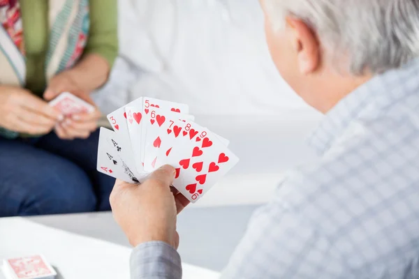 Senior Man Playing Cards With Female Friend