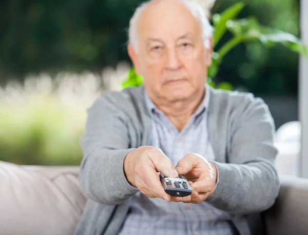 Senior Man Using Remote Control While Sitting On Couch