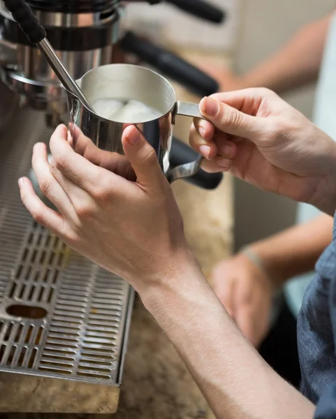 Barista Steaming Milk In Coffeeshop