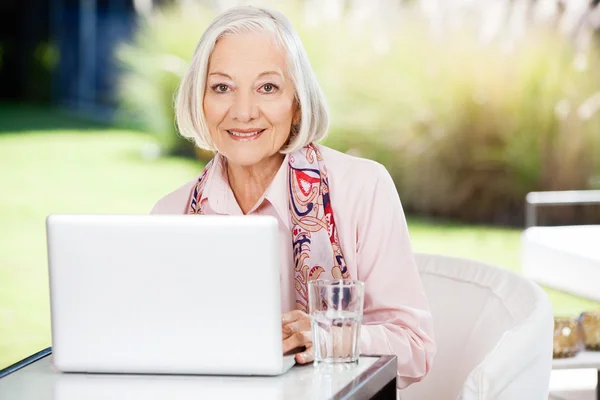 Senior Woman Using Laptop At Nursing Home Porch