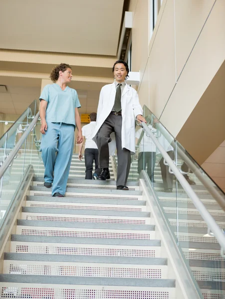 Nurse And Doctor Walking Down Stairs In Hospital