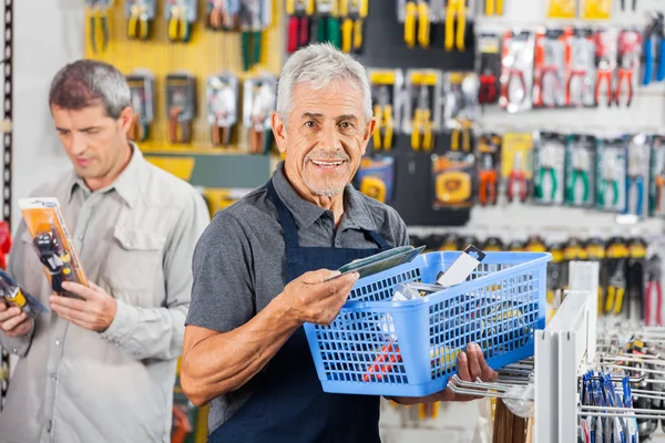 Salesman Holding Tools Basket At Hardware Store