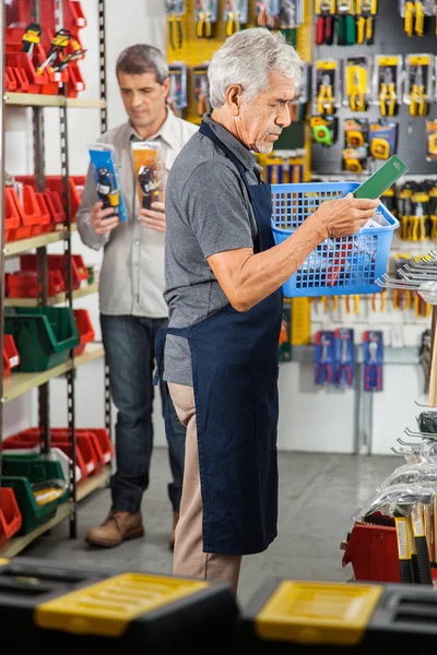 Senior Worker Holding Tool Basket In Store