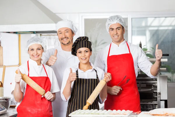 Confident Chef Team Gesturing Thumbsup In Kitchen