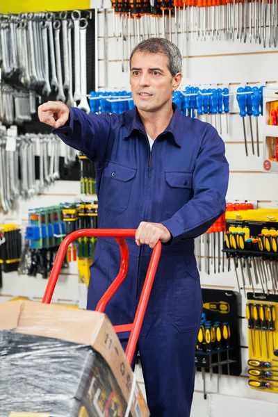 Worker With Trolley Pointing In Hardware Shop