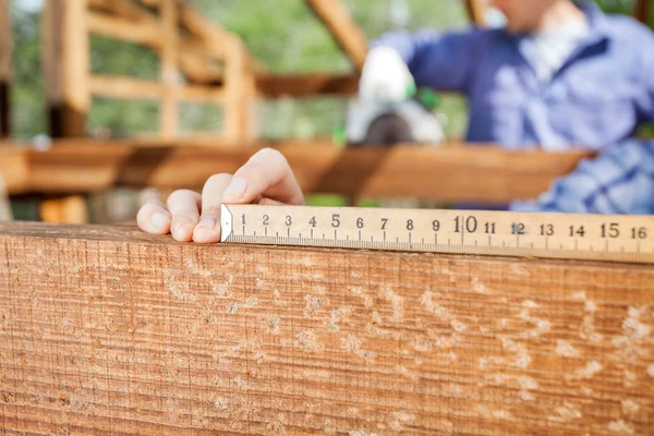 Architects Hand Measuring Wood At Site