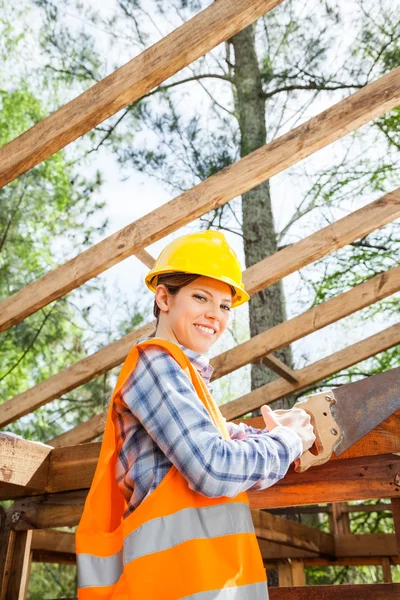 Female Worker Cutting Wood With Handsaw At Site