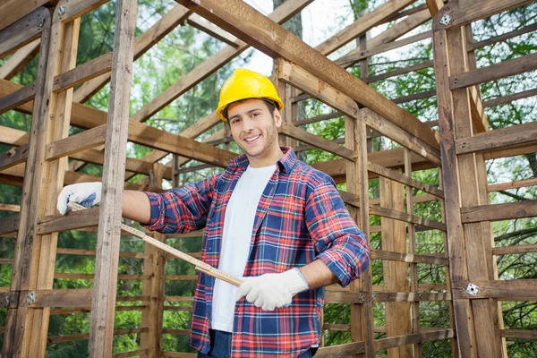 Happy Carpenter Holding Measure Tape At Construction Site