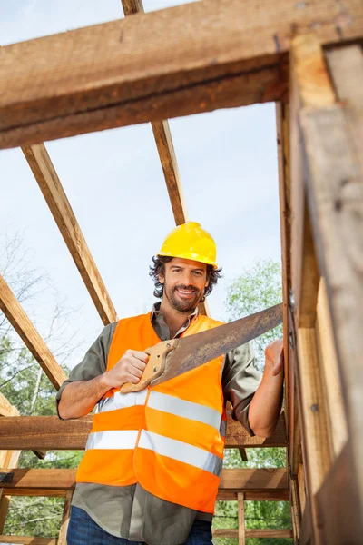Smiling Worker Cutting Wood With Handsaw At Site