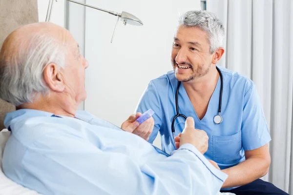 Happy Caretaker Discussing Prescription With Senior Man