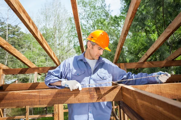 Construction Worker Measuring Timber Frame