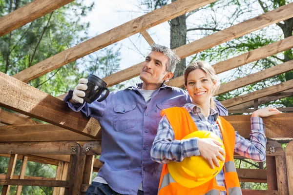 Happy Construction Worker Standing With Colleague Holding Coffee