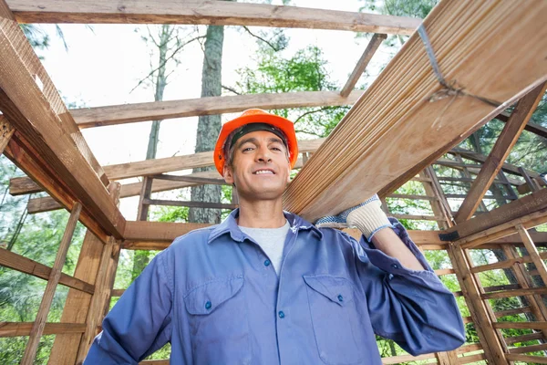 Smiling Construction Worker Carrying Wooden Planks