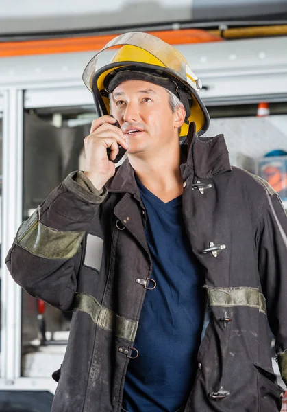 Mature Fireman Using Walkie Talkie At Fire Station