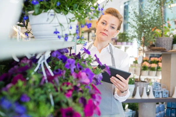Florist Holding Digital Tablet While Standing By Flower Trolley