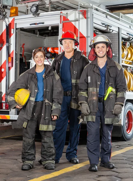 Portrait Of Confident Firefighters Standing Against Truck