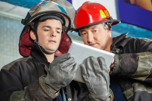 Male Firefighters Using Digital Tablet At Fire Station