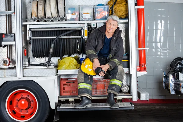 Confident Fireman Sitting In Truck At Fire Station