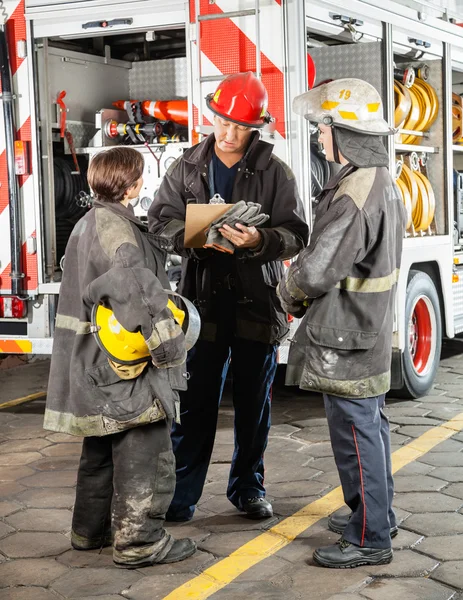 Firefighters Discussing Over Clipboard At Fire Station