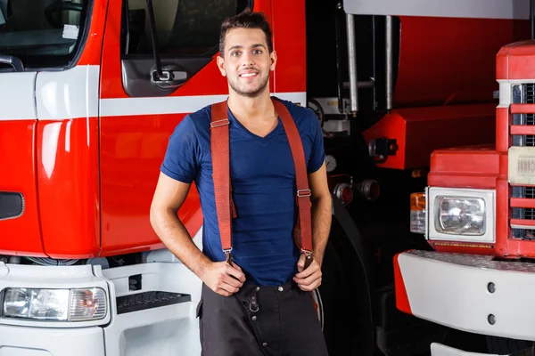 Smiling Fireman Standing Against Trucks