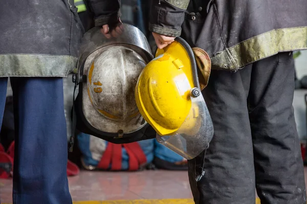 Firemen Holding Helmets At Fire Station