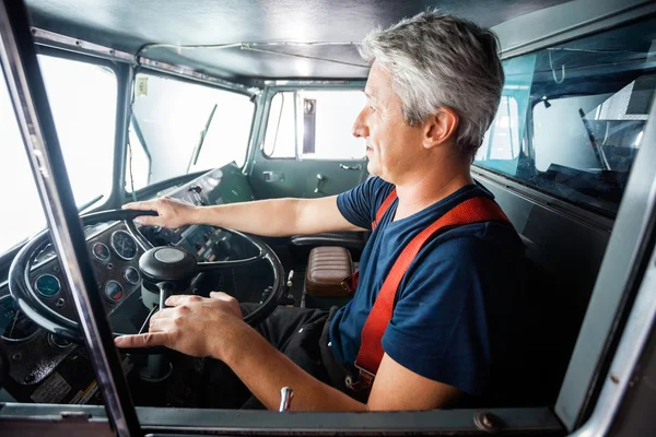 Mature Fireman Driving Firetruck