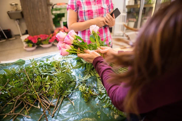 Florist Making Bouquet Of Roses For Female Customer