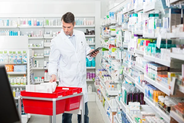Male Pharmacist Counting Stock While Holding Digital Tablet