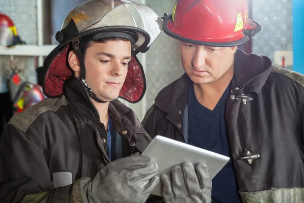 Firemen Using Digital Tablet At Fire Station