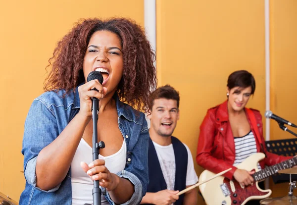 Female Singer Performing With Band Members In Recording Studio