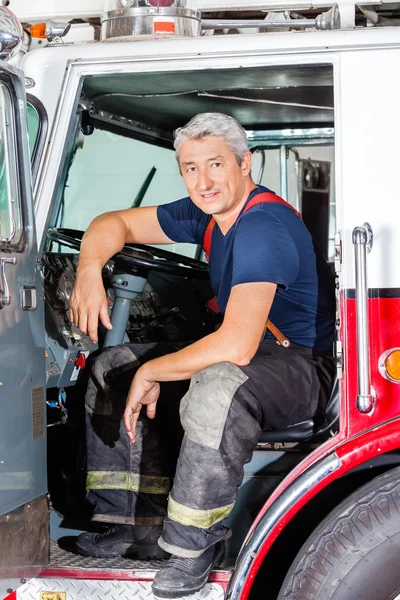 Smiling Male Firefighter Sitting In Truck