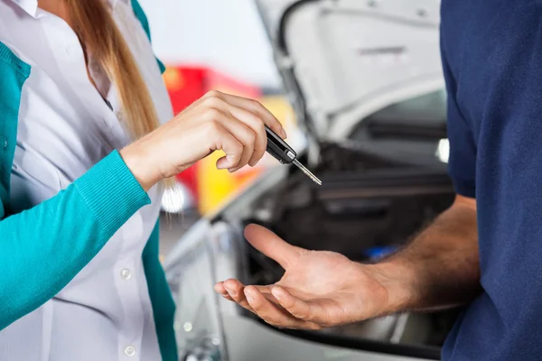 Customer Giving Car Keys To Mechanic