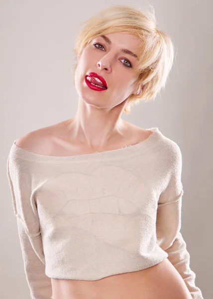 The blond woman with short hair and a beautiful smile with red lips isolated. Touches the lips